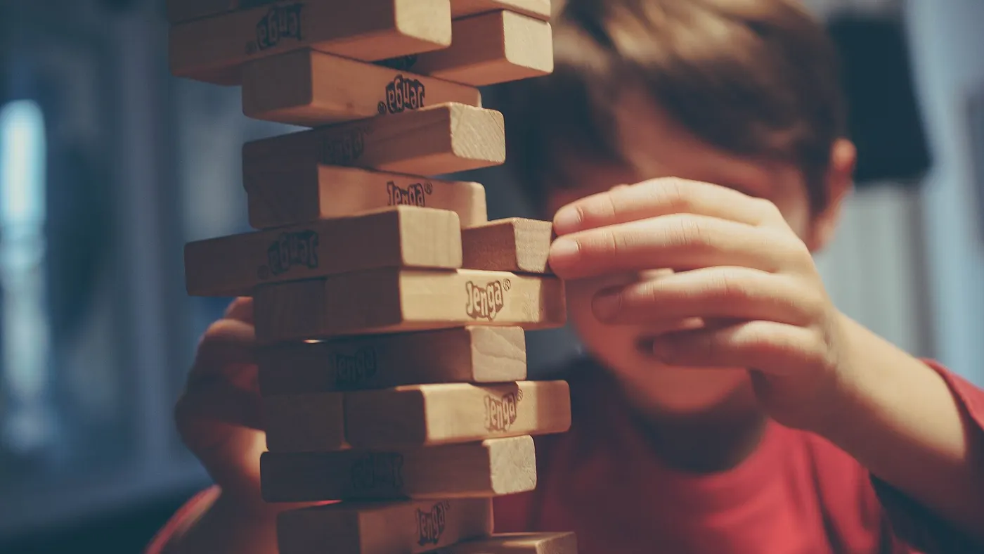 Un enfant concentré sur une tour de blocs en bois