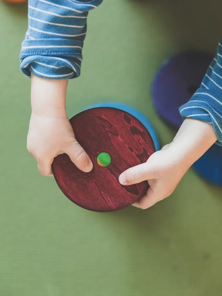 Les mains d'un enfant manipulant un disque en bois, matériel Montessori